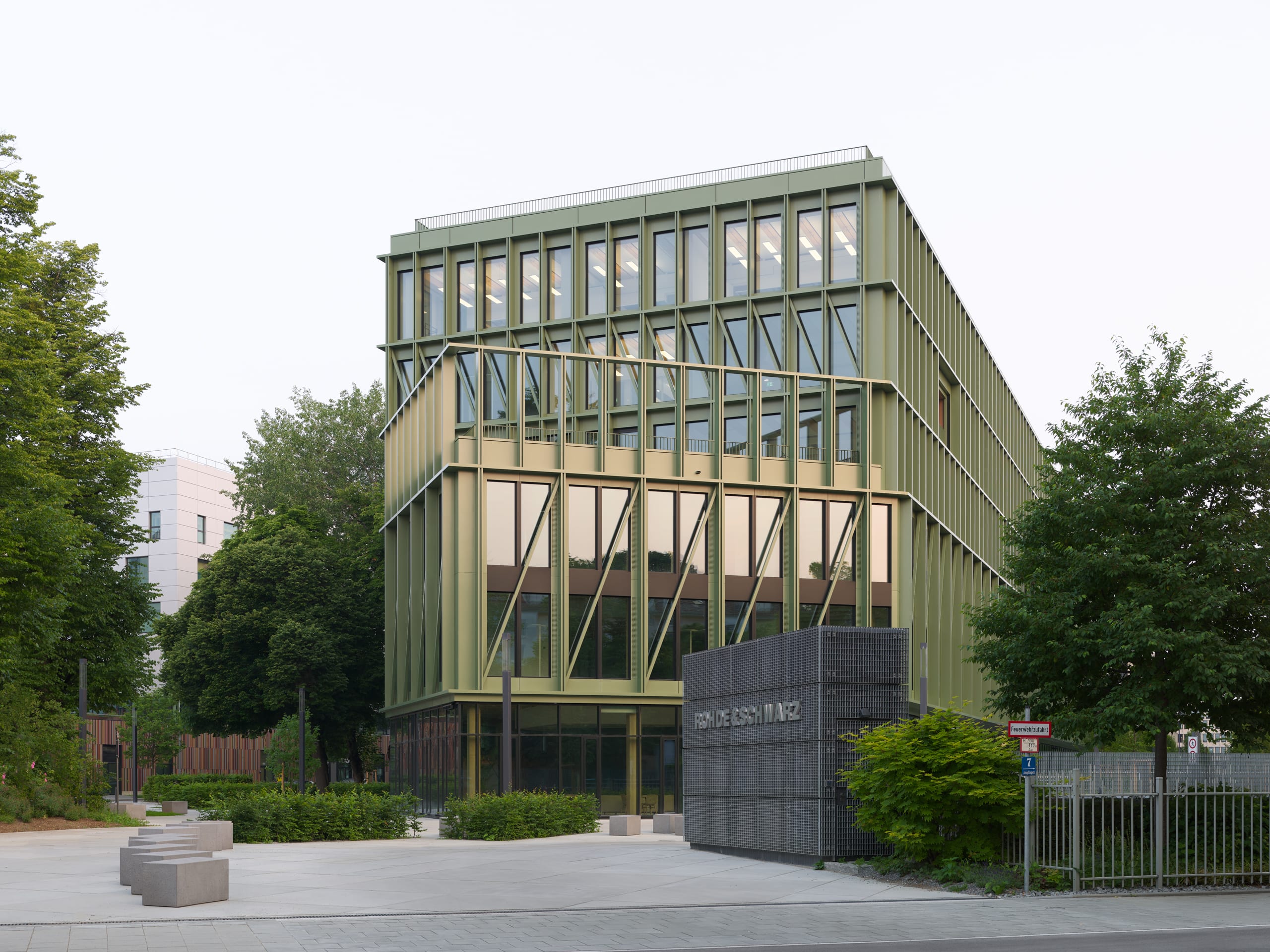 Modernes Gebäude mit großen Fenstern und grüner Fassade.