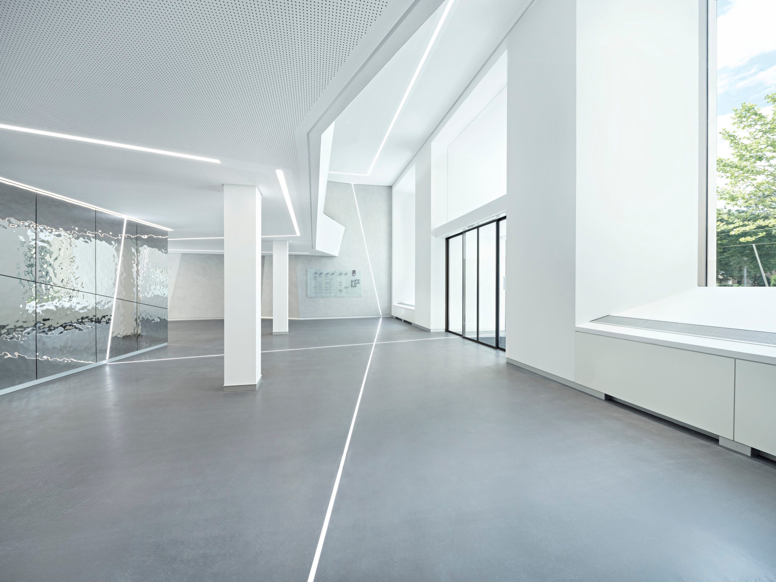 Modernes, helles Foyer mit Glas und Betonsäulen.