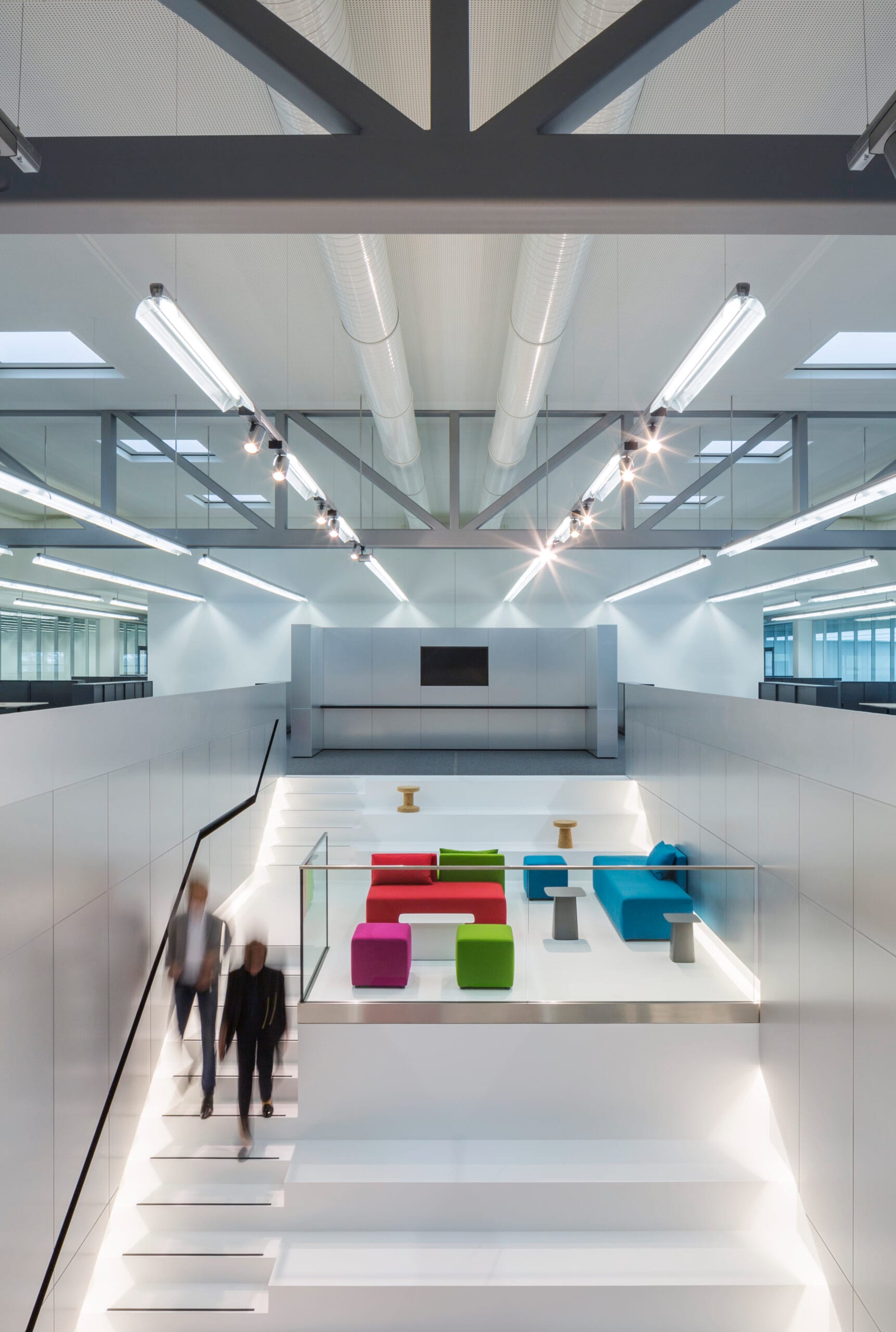 Moderner Innenraum mit bunten Sitzgelegenheiten und Treppen.