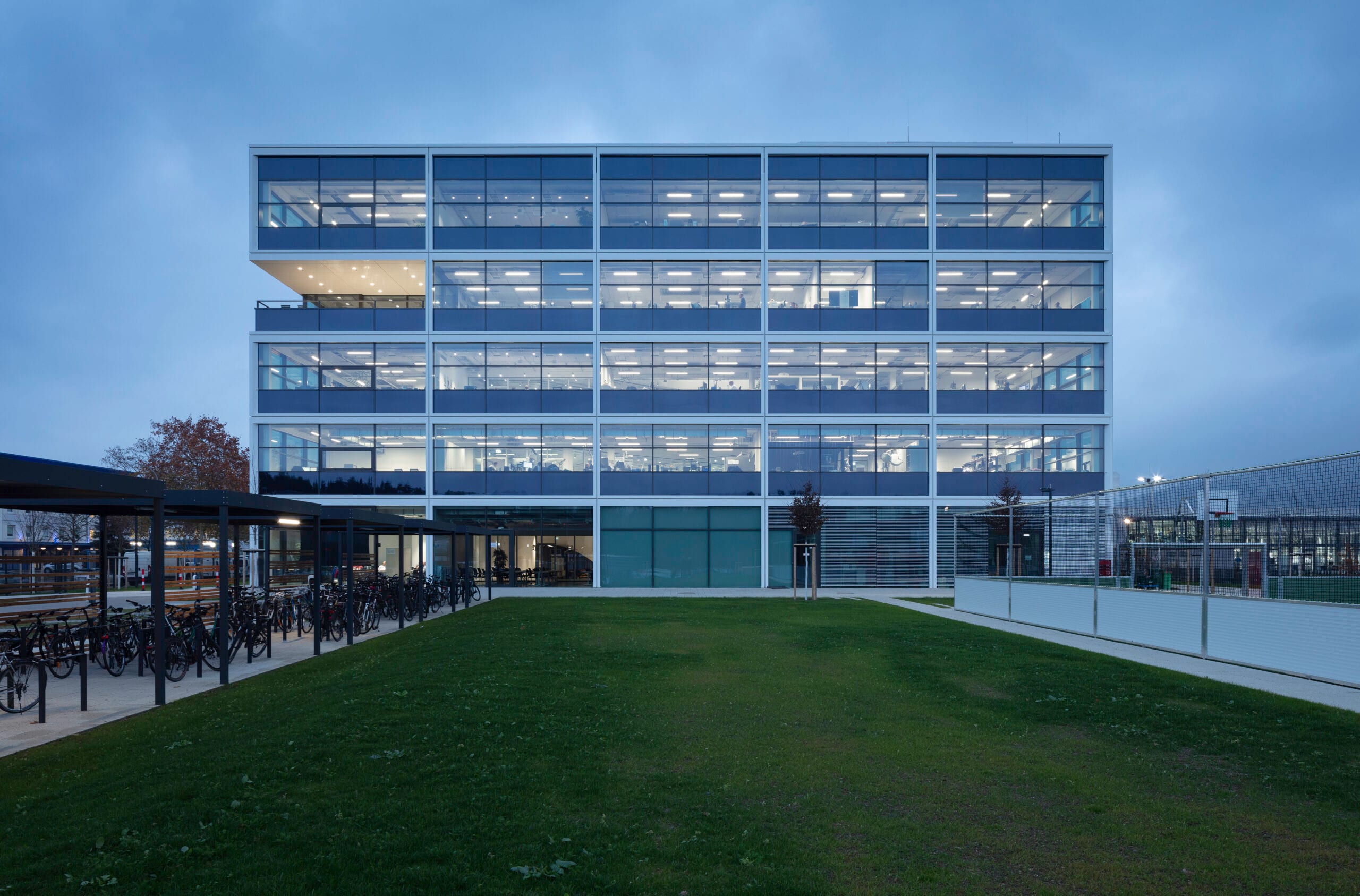 Modernes beleuchtetes Bürogebäude bei Dämmerung.
