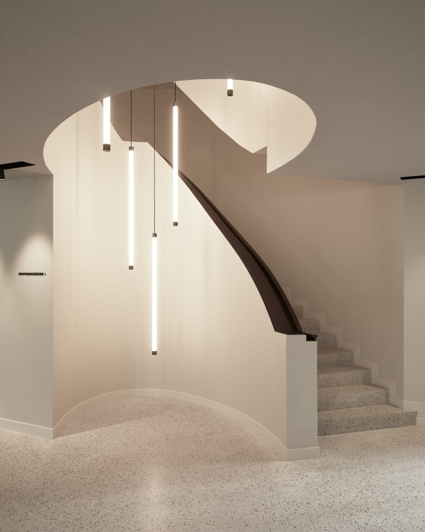 Minimalistische Treppe mit hängenden Leuchten in modernem Design.