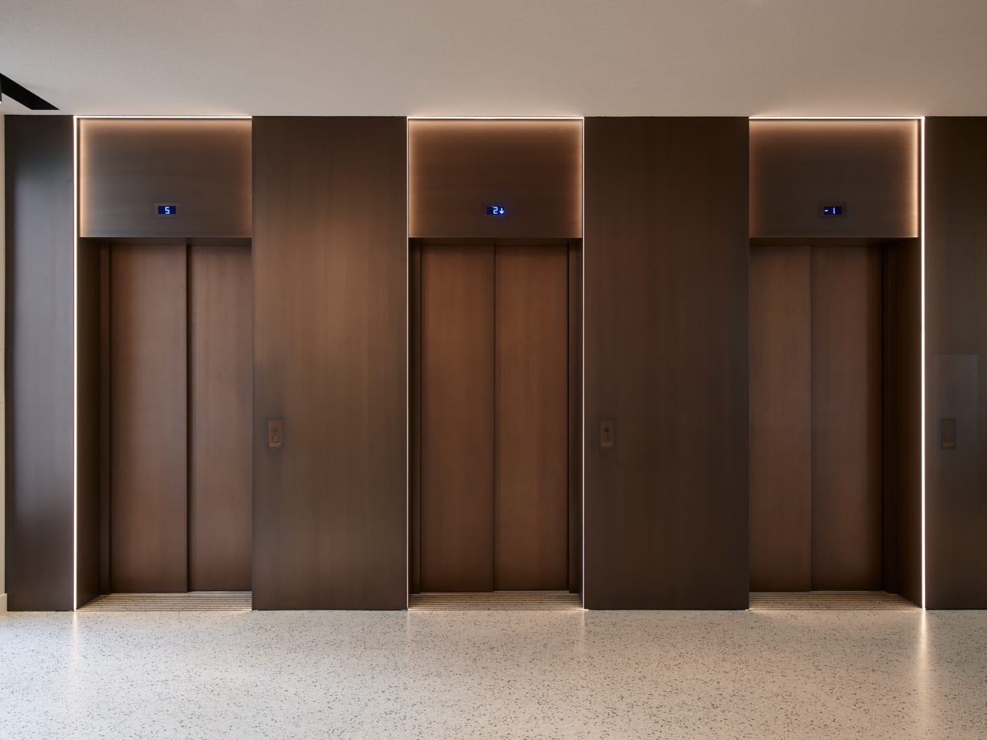 Vier geschlossene Aufzüge in modernem Gebäudeflur.