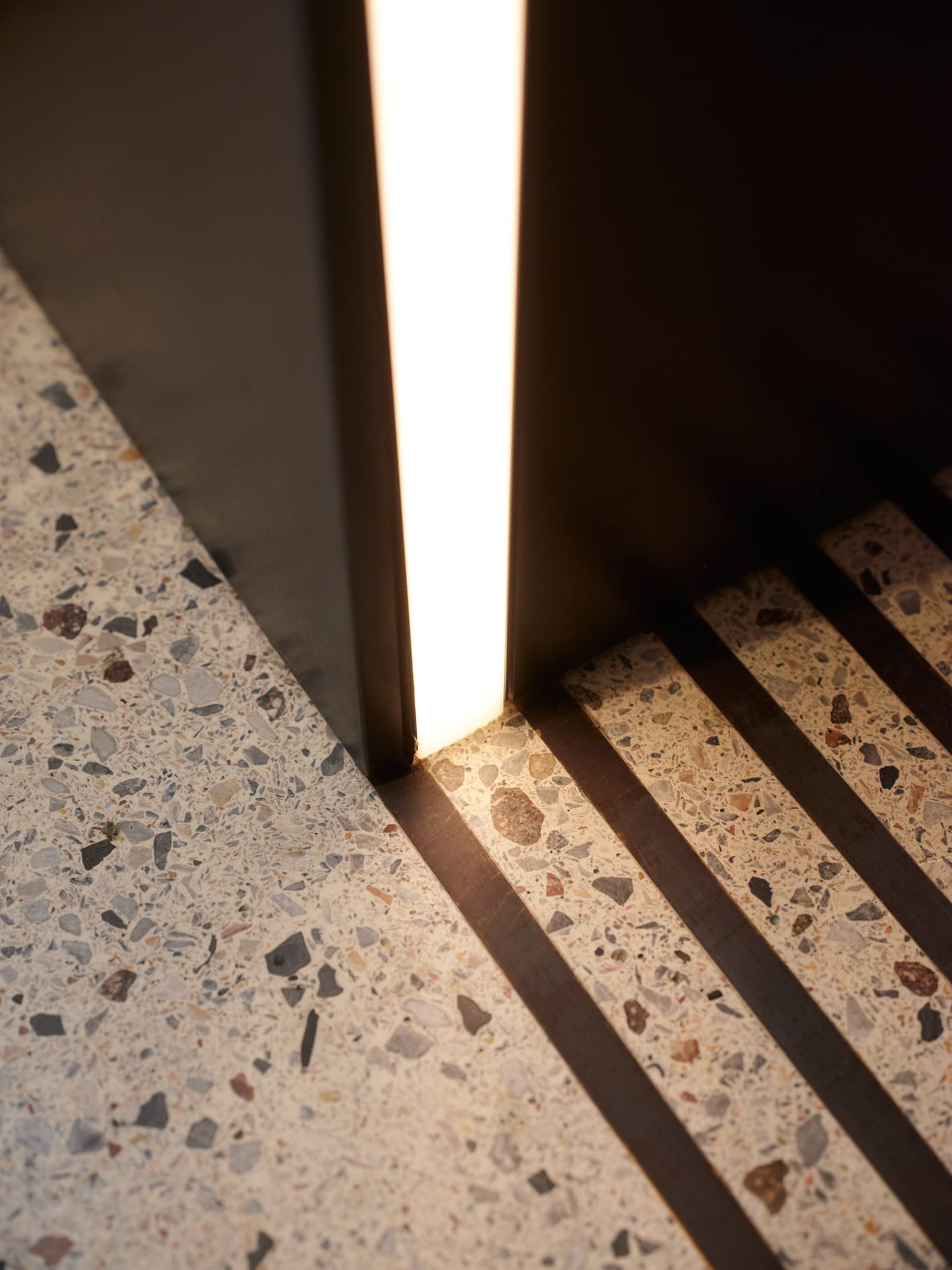 Leuchte an Terrazzo-Boden mit Schattenlinien.
