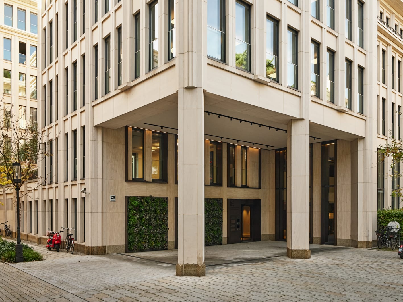 Moderne Gebäudefassade mit Eingangsbereich und Pflanzenwand.