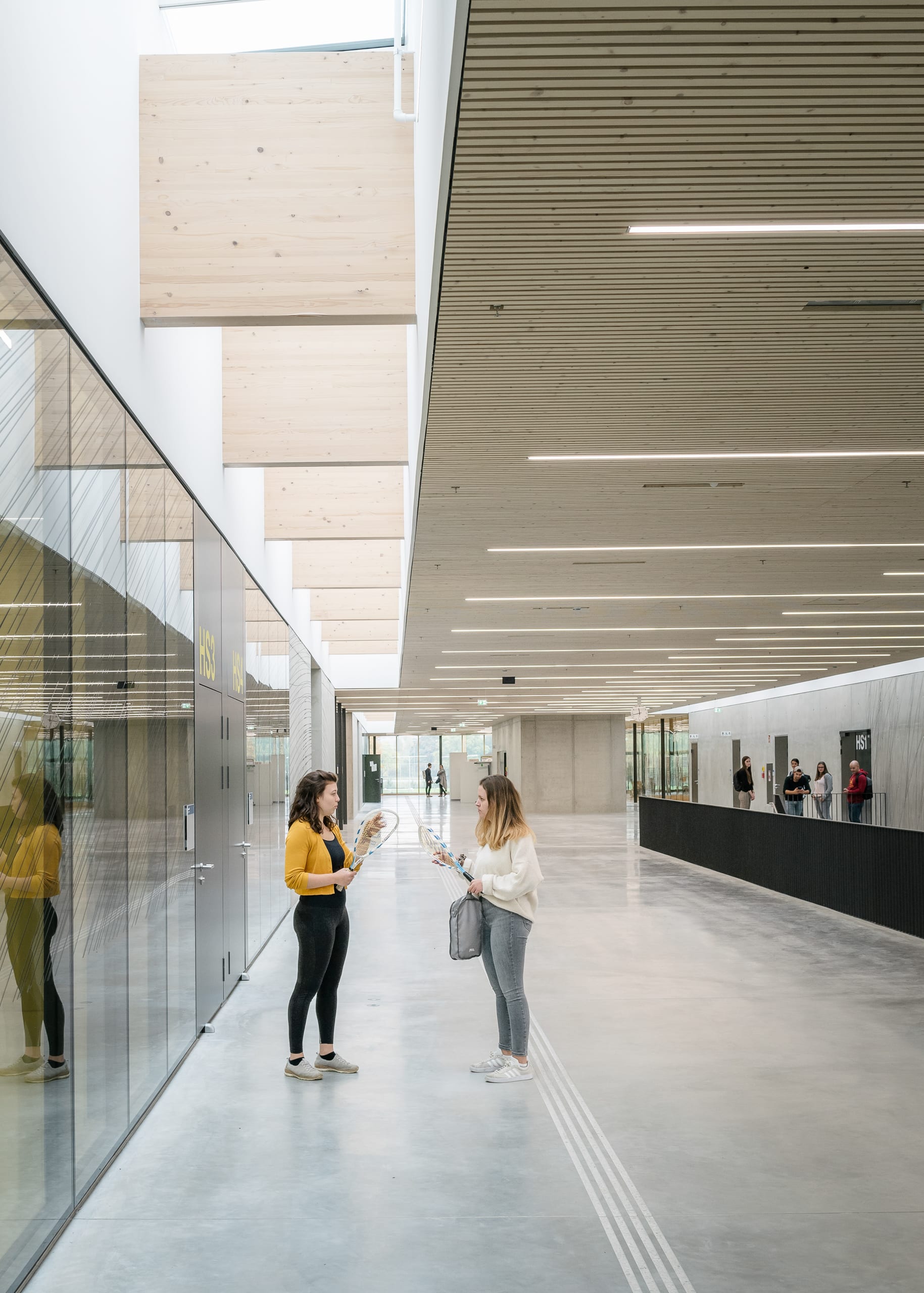 Zwei Frauen mit Badmintonschlägern in modernem, Gebäude, mit angenehmer Beleuchtung