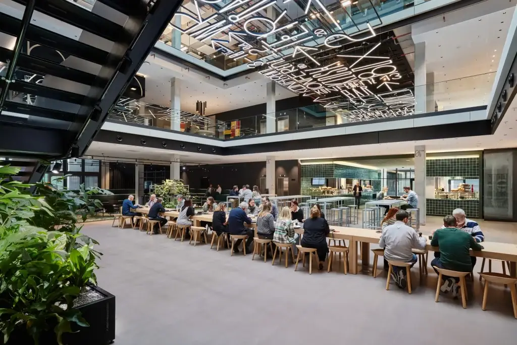 Modern office canteen with people and plants.