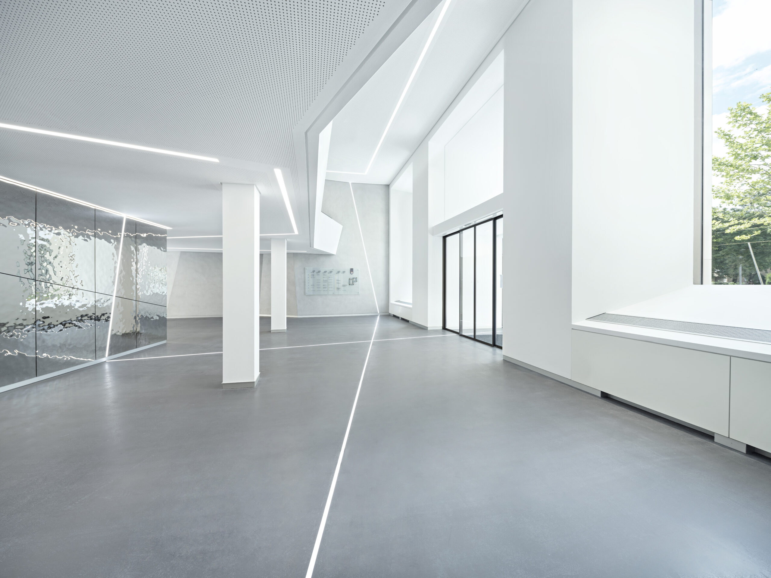 Modernes, helles Foyer mit Glas und Betonsäulen.