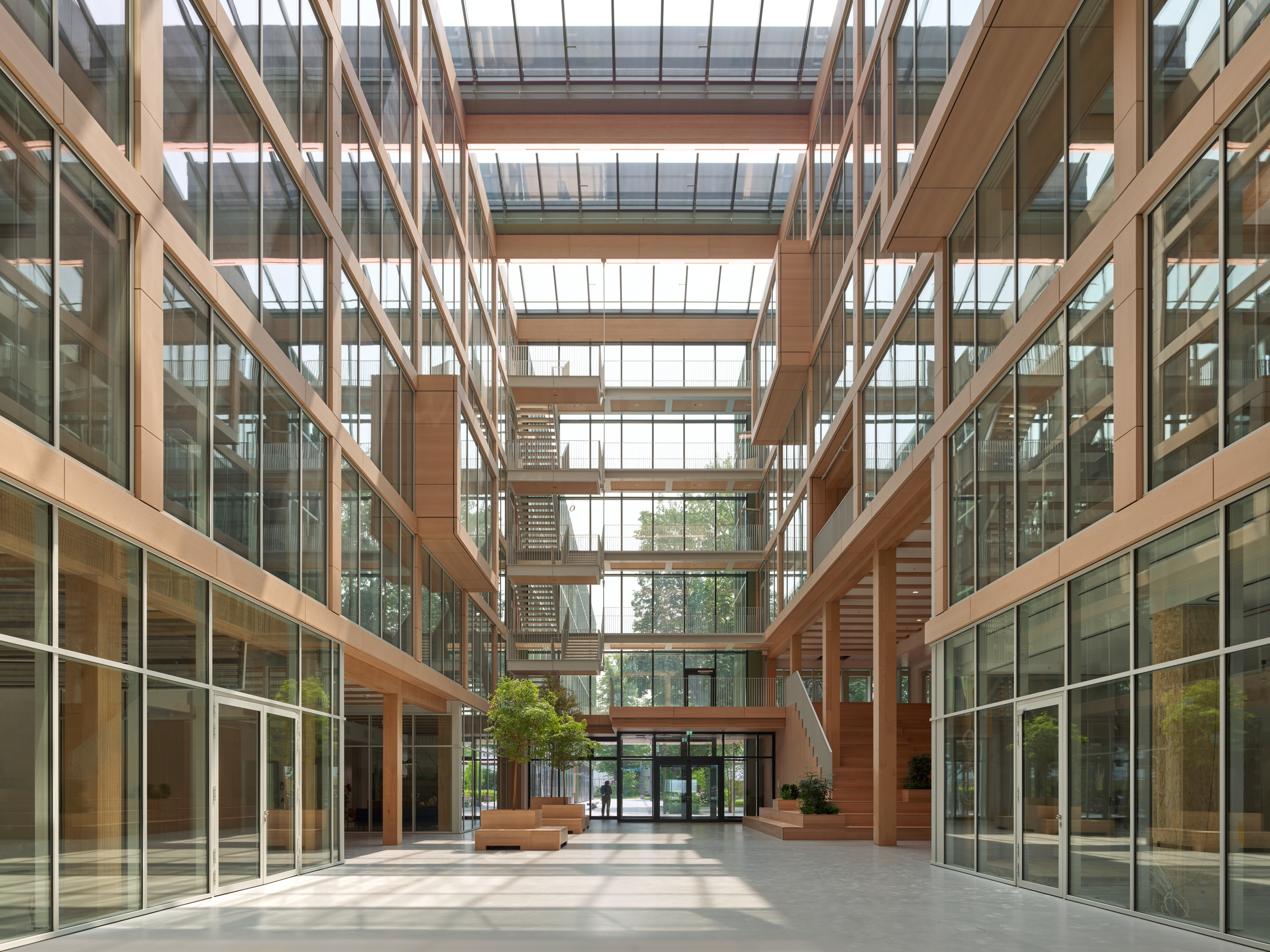 Modernes Atrium mit Glasfassaden und Pflanzen.